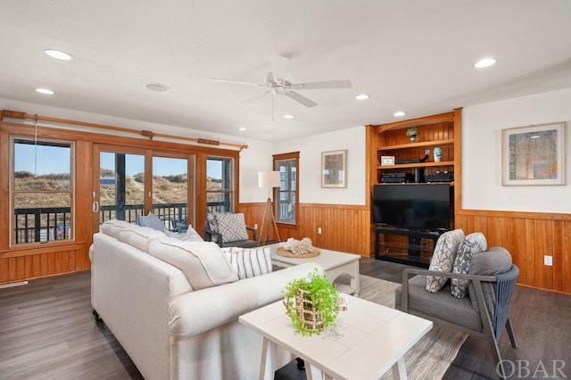 living room featuring wood walls, dark wood-type flooring, and wainscoting