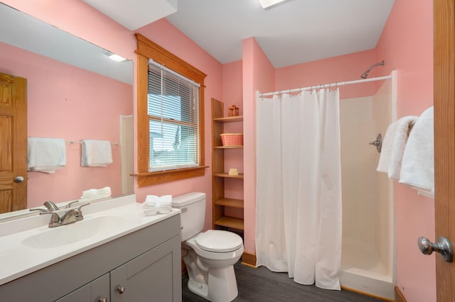 bathroom featuring toilet, wood finished floors, a shower stall, and vanity