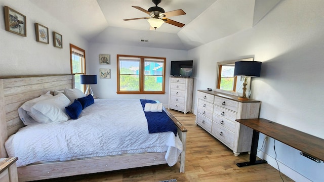 bedroom featuring light wood-style floors, lofted ceiling, visible vents, and a ceiling fan