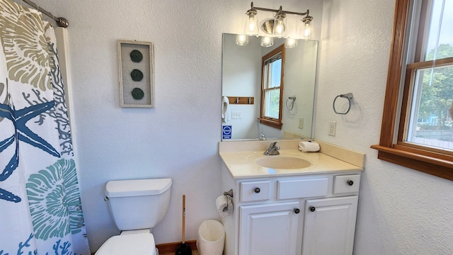 bathroom with toilet, a textured wall, and vanity