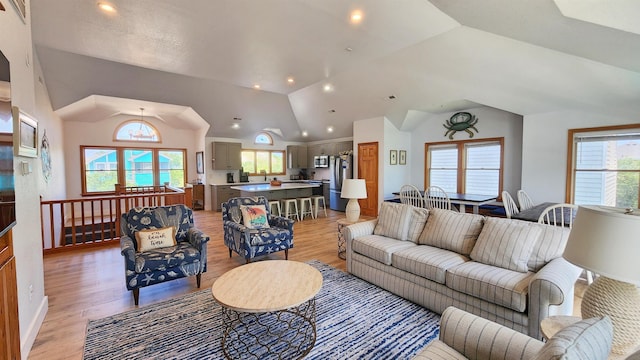 living room with lofted ceiling, light wood finished floors, and a wealth of natural light