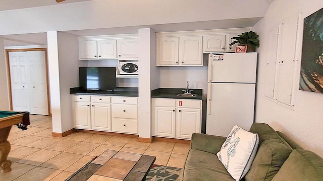 kitchen with dark countertops, freestanding refrigerator, open floor plan, white cabinetry, and built in microwave