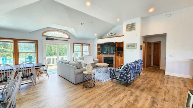 living area featuring light wood-style flooring, visible vents, and a glass covered fireplace