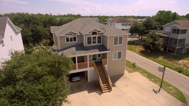 view of front facade featuring a shingled roof, driveway, a porch, and stairway