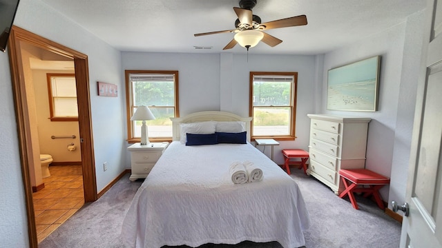 carpeted bedroom featuring visible vents, ensuite bathroom, baseboards, and multiple windows