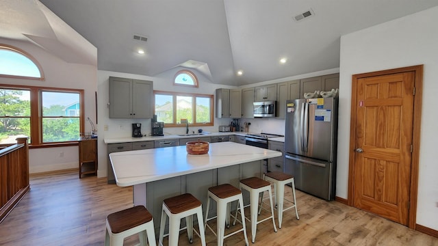 kitchen featuring visible vents, a center island, stainless steel appliances, light countertops, and a sink