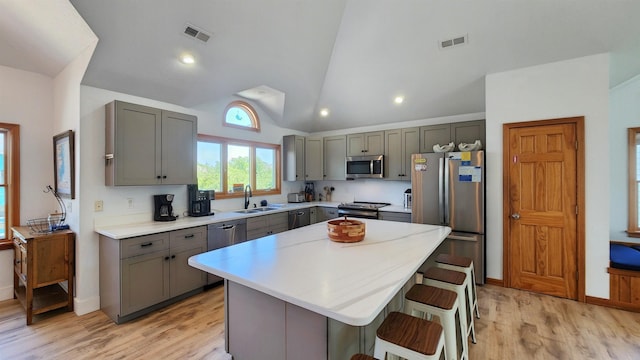 kitchen with visible vents, a kitchen island, a kitchen breakfast bar, stainless steel appliances, and light countertops