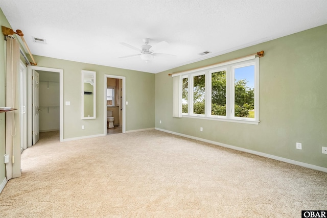 1115 Waterlily Rd, Coinjock, NC 27923 - unfurnished bedroom featuring light carpet, a walk in closet, ensuite bathroom, a ceiling fan, and a closet