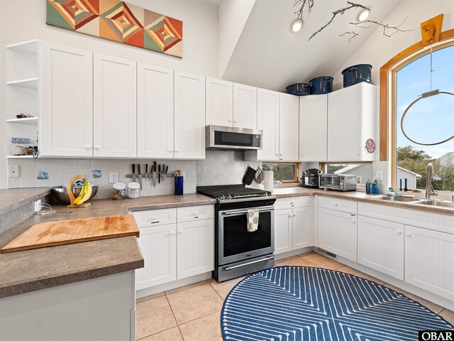 kitchen featuring a sink, backsplash, open shelves, appliances with stainless steel finishes, and light tile patterned floors