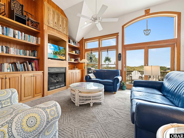 living room featuring a fireplace, high vaulted ceiling, ceiling fan, and built in shelves