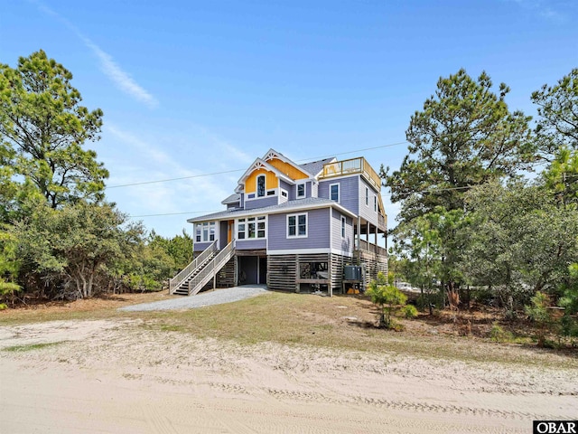 view of front of property with central air condition unit, stairs, and dirt driveway
