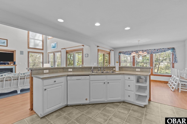 kitchen featuring white dishwasher, light countertops, white cabinetry, a sink, and recessed lighting