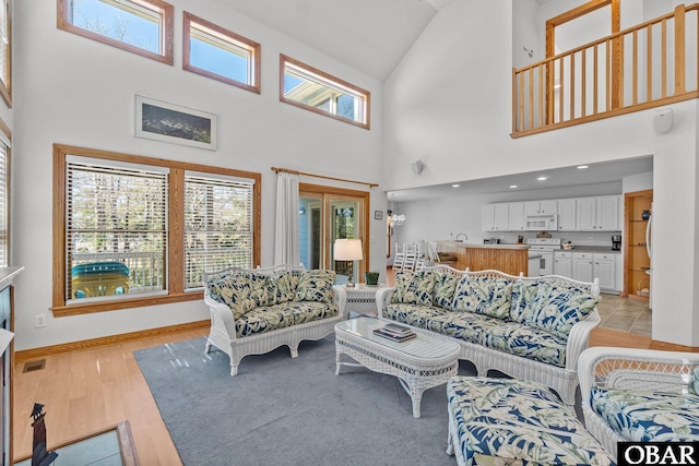 living room with visible vents, light wood-style flooring, and baseboards