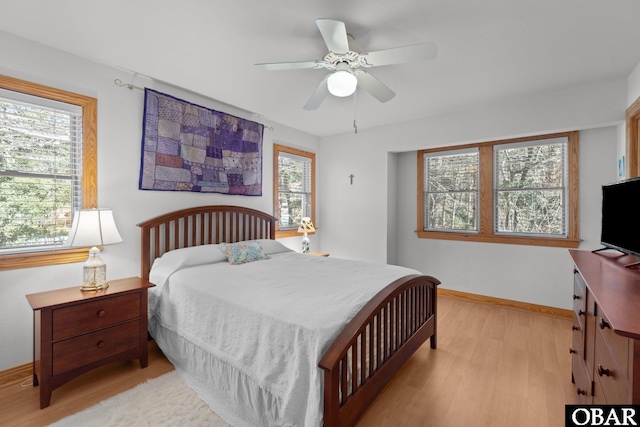 bedroom featuring ceiling fan, multiple windows, light wood-type flooring, and baseboards