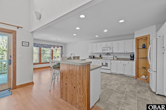 kitchen with a kitchen breakfast bar, white appliances, recessed lighting, and white cabinets