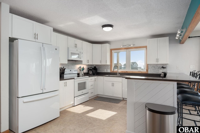 42082 Ocean View Dr Lot 67, Avon, NC 27915 - kitchen featuring white appliances, dark countertops, tasteful backsplash, a breakfast bar, and white cabinetry