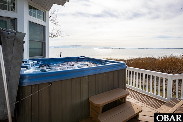balcony with a deck with water view and a hot tub