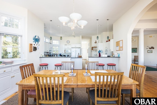 dining room featuring arched walkways, a chandelier, and light wood-type flooring