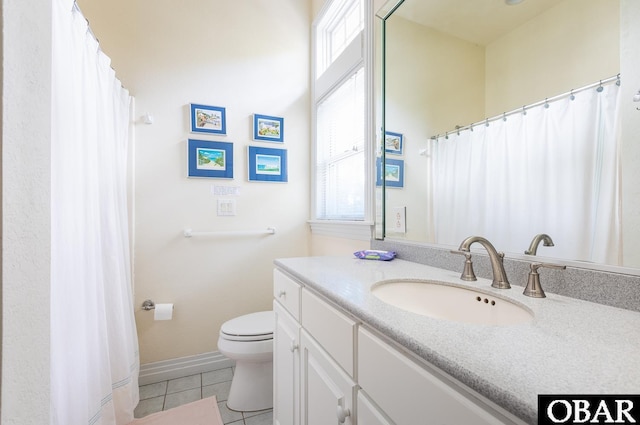 bathroom with tile patterned floors, vanity, toilet, and a healthy amount of sunlight