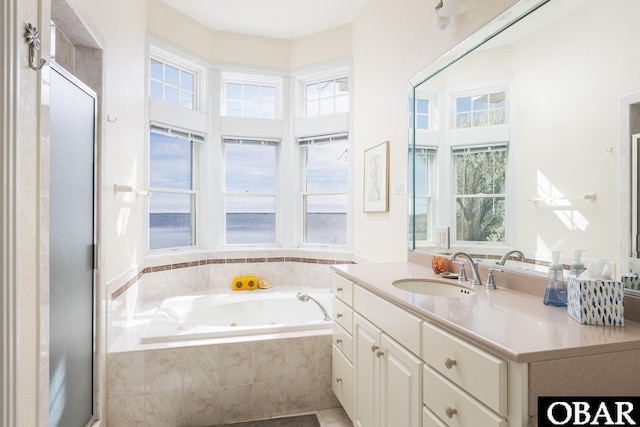 bathroom featuring a tub with jets, vanity, and a wealth of natural light