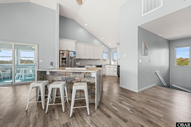 1024 Lighthouse Dr Lot 14, Corolla, NC 27927 - kitchen with stainless steel appliances, white cabinetry, wood finished floors, a kitchen breakfast bar, and high vaulted ceiling