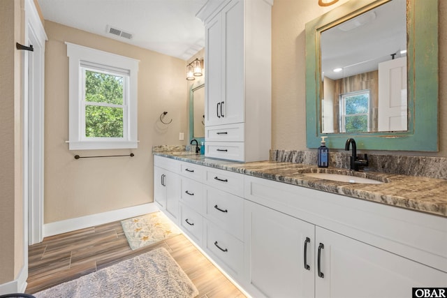 full bath featuring wood finished floors, visible vents, a sink, and double vanity