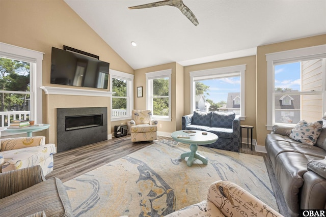 living room with lofted ceiling, light wood finished floors, plenty of natural light, and a glass covered fireplace