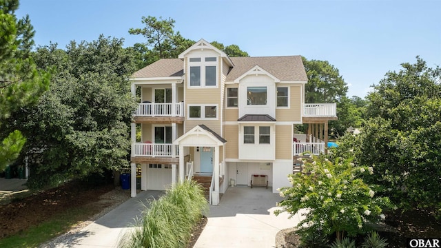 view of front of home with a shingled roof, driveway, a balcony, and an attached garage