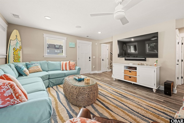 living area with dark wood-type flooring, visible vents, baseboards, and a ceiling fan