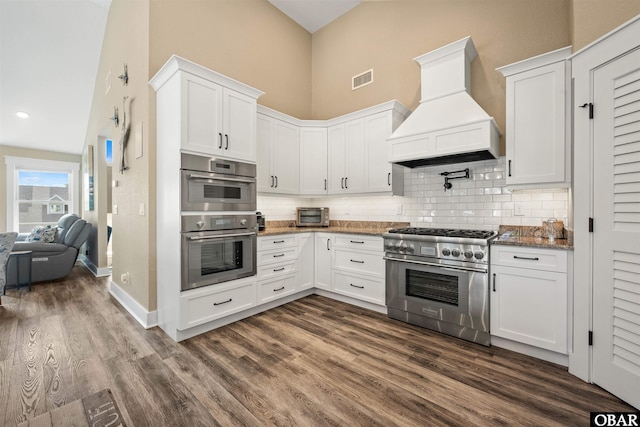 kitchen featuring white cabinetry, premium range hood, and appliances with stainless steel finishes