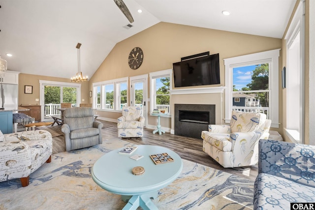 living room with visible vents, dark wood finished floors, an inviting chandelier, a fireplace, and high vaulted ceiling