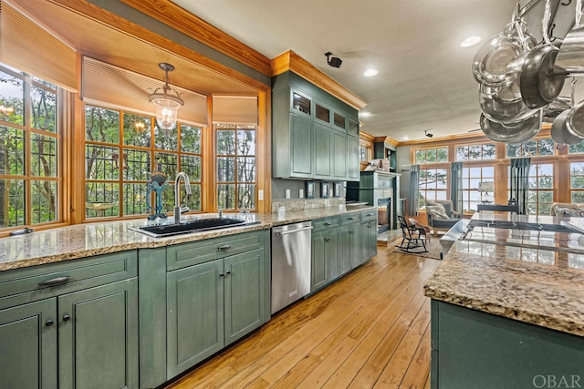 kitchen featuring green cabinetry, dishwasher, glass insert cabinets, hanging light fixtures, and a sink