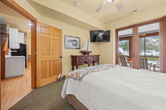 bedroom featuring visible vents, a ceiling fan, light colored carpet, access to outside, and a sink