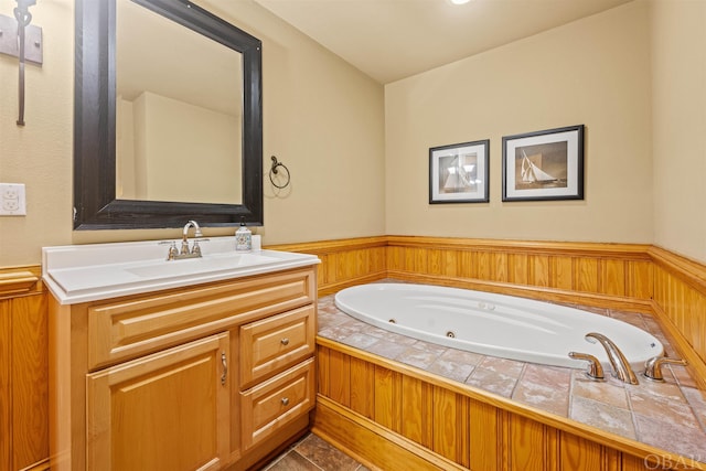 full bathroom with a wainscoted wall, a jetted tub, and vanity