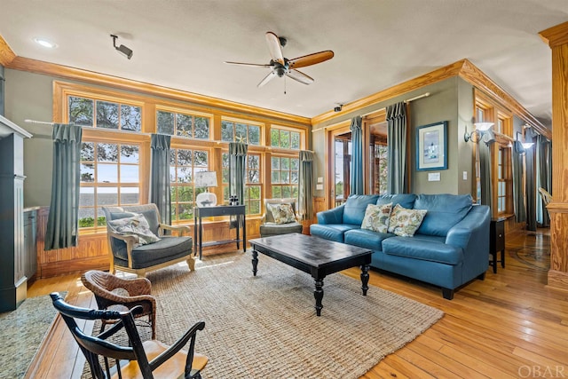 living area featuring ceiling fan, light wood-style flooring, and crown molding