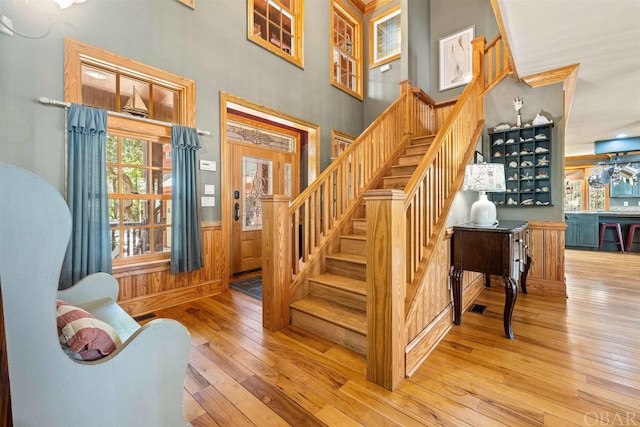 stairway with a wainscoted wall and wood finished floors