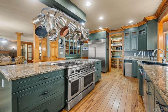 kitchen with premium appliances, ornate columns, a sink, and light stone counters