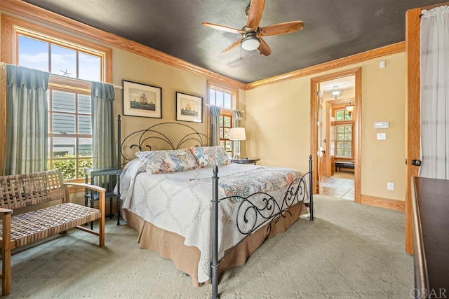 bedroom featuring light carpet, crown molding, baseboards, and ceiling fan