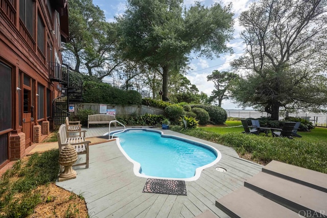 view of swimming pool featuring a fenced in pool, a yard, fence, a wooden deck, and stairs