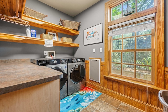 laundry area featuring laundry area, separate washer and dryer, a wainscoted wall, and wood walls