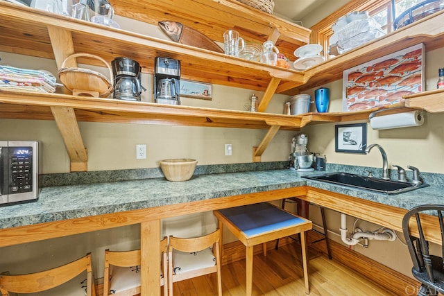 kitchen featuring stainless steel microwave, a sink, and wood finished floors