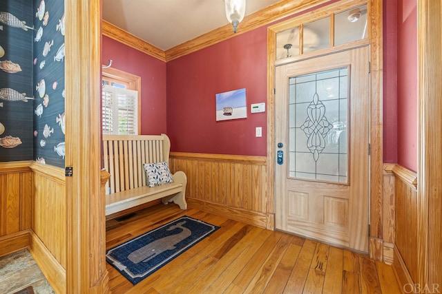 entrance foyer with a wainscoted wall, crown molding, wooden walls, and wood finished floors