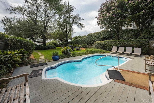 pool featuring a yard, a wooden deck, and fence