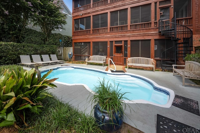 outdoor pool featuring a sunroom, a patio, stairway, and fence