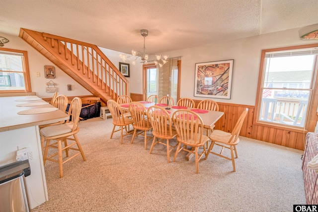 58208 Sand Rd Lot 19, Hatteras, NC 27943 - carpeted dining room featuring wainscoting, a chandelier, a textured ceiling, stairway, and wooden walls