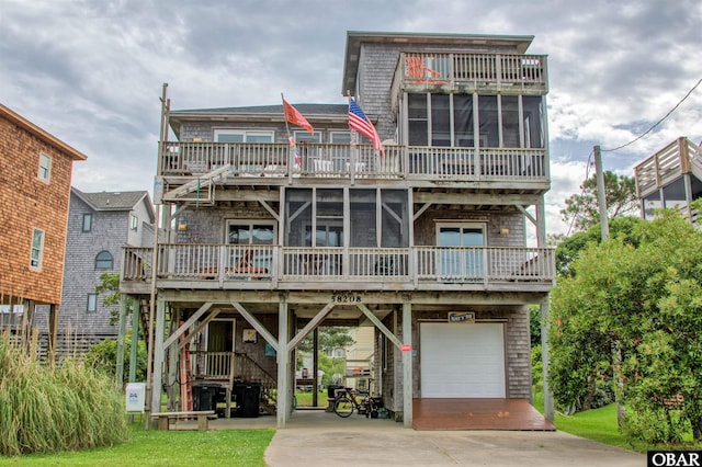 58208 Sand Rd Lot 19, Hatteras, NC 27943 - back of house with concrete driveway, an attached garage, a sunroom, a carport, and a balcony