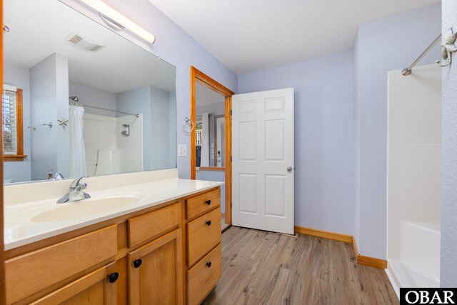 bathroom featuring visible vents, vanity, wood finished floors, a shower with curtain, and baseboards