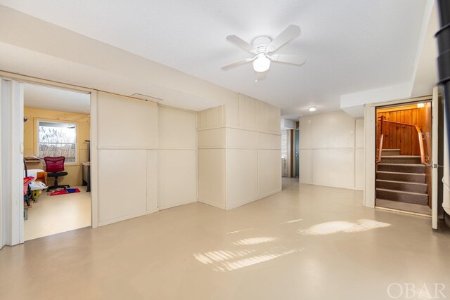 empty room with stairs, a ceiling fan, and finished concrete floors