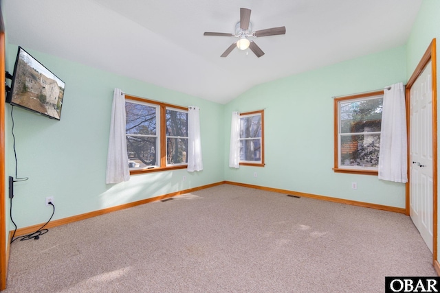 interior space with lofted ceiling, a ceiling fan, visible vents, and baseboards