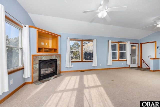 unfurnished living room with lofted ceiling, plenty of natural light, ceiling fan, and a tile fireplace